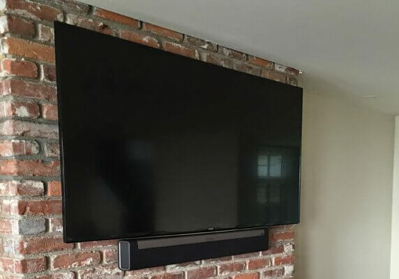 The Playbar and TV are mounted to a brick fireplace.